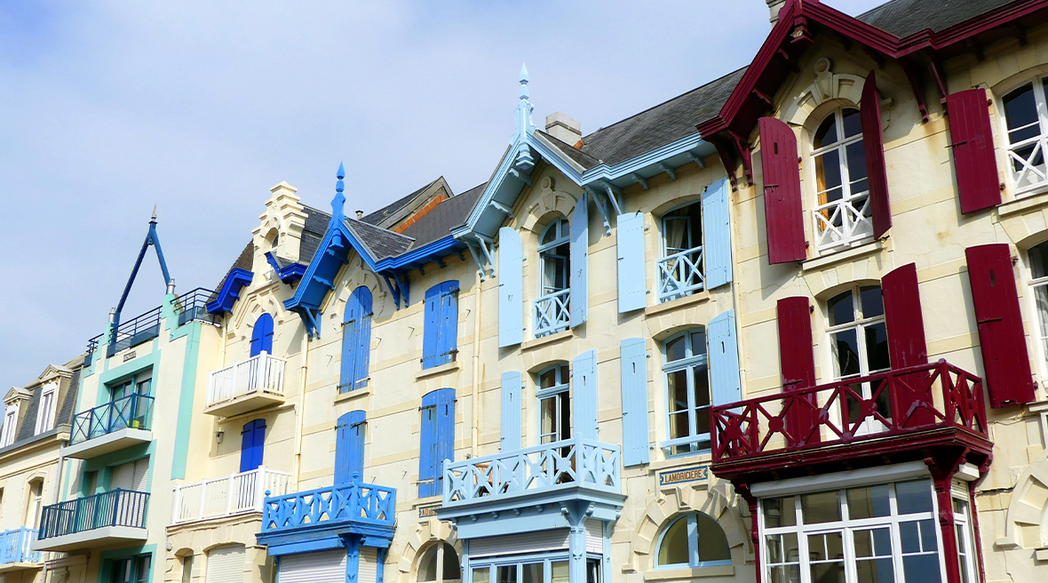blue green red and yellow painted terrace of detailed houses with blue skies above